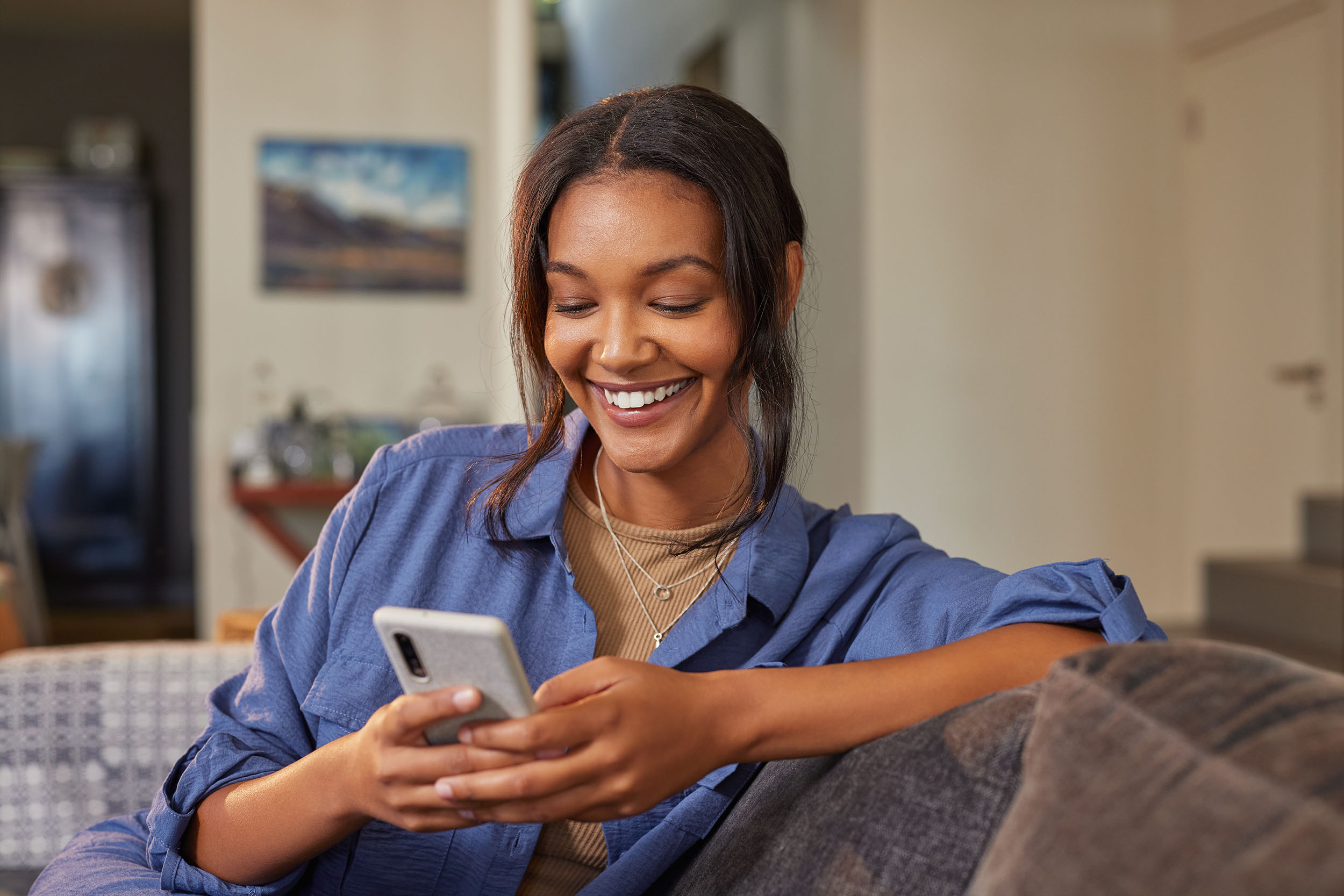 En kvinna som sitter i en soffa och använder en telefon.